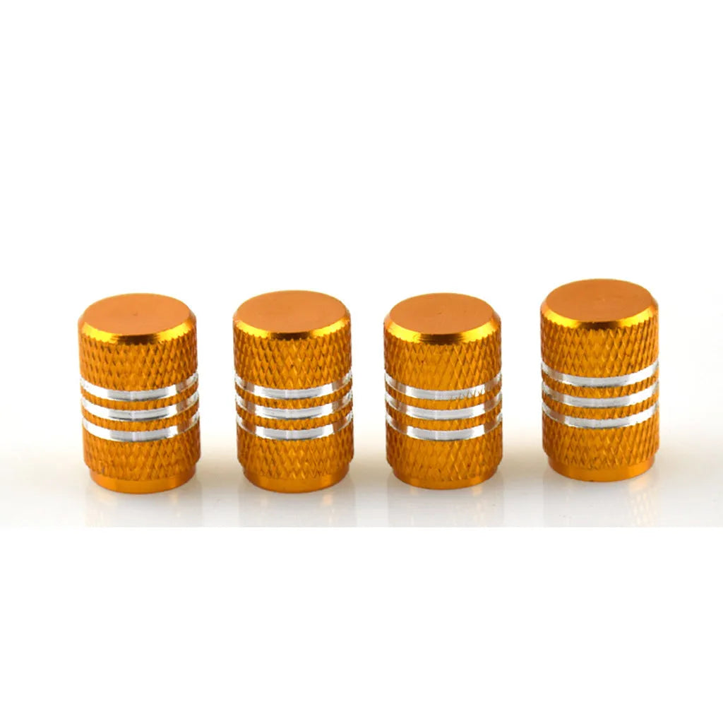 Set of coloured aluminium alloy tyre valve caps for car wheels on a grey background.