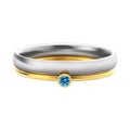 Geometric titanium steel ring with engraved detail and December birthstone colour combination on a finger.