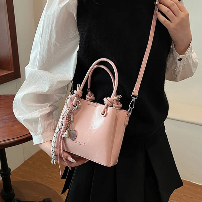Women's PU one-shoulder bucket messenger bag in black with pendant, showing front view with single strap