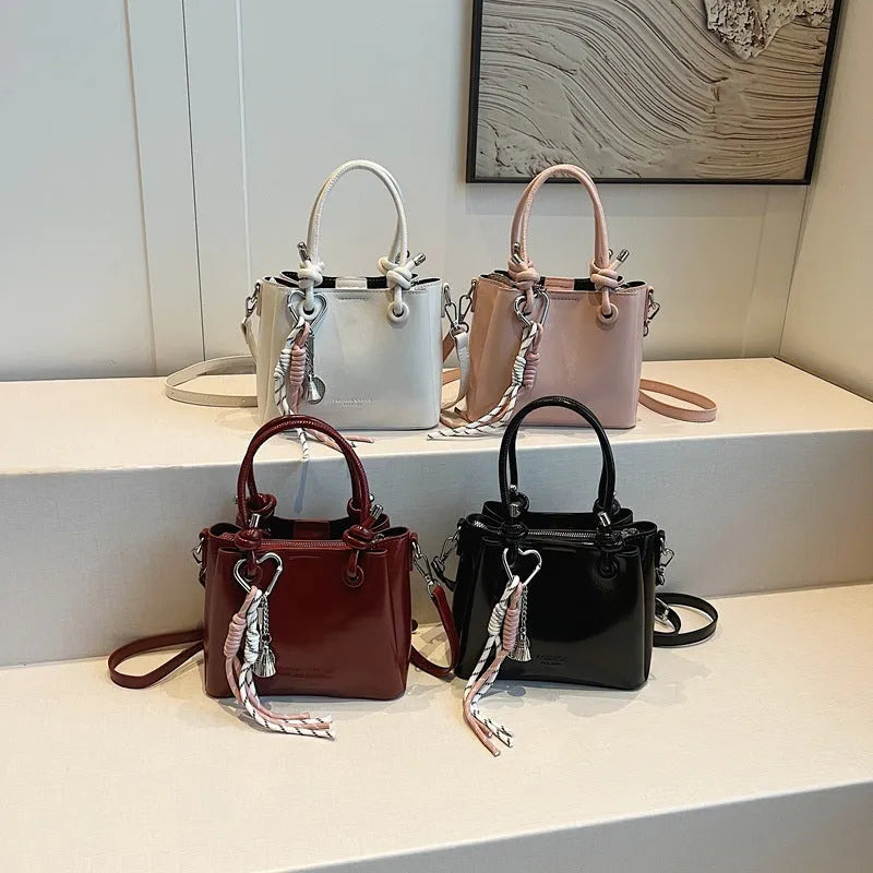 Women's PU one-shoulder bucket messenger bag in black with pendant, showing front view with single strap