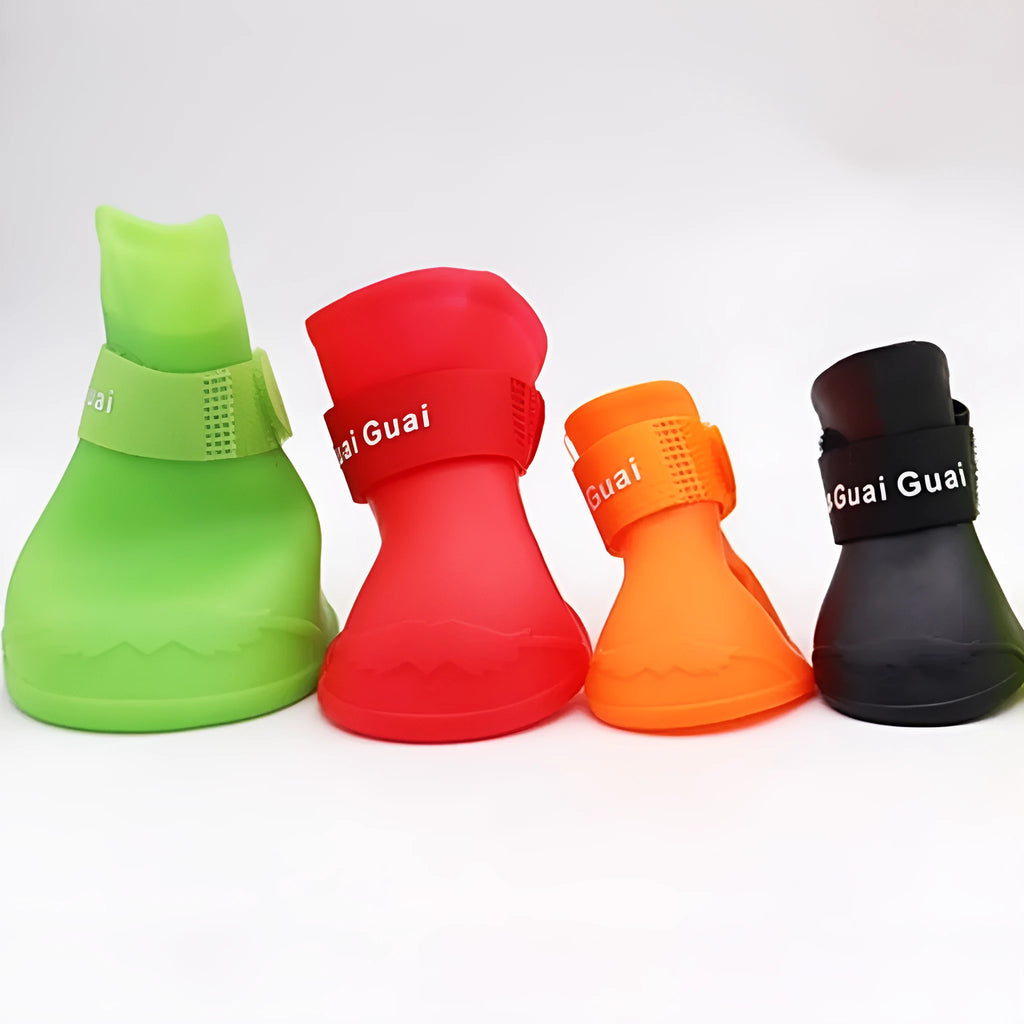 Set of four colourful rubber dog rain shoes with anti-slip soles on a wet surface.