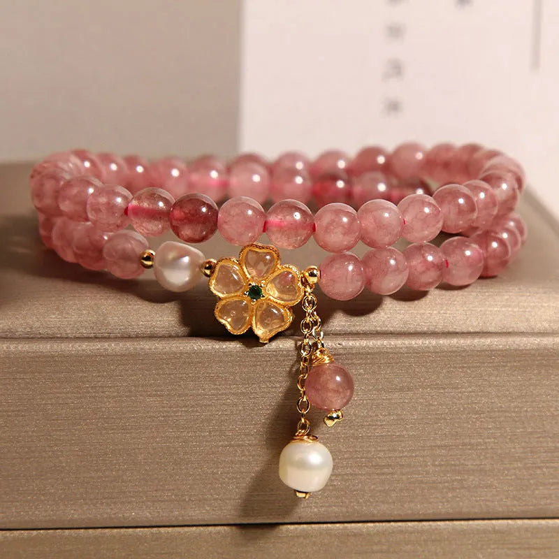Women's double ring bracelet with strawberry quartz four-leaf clover charms on wrist.