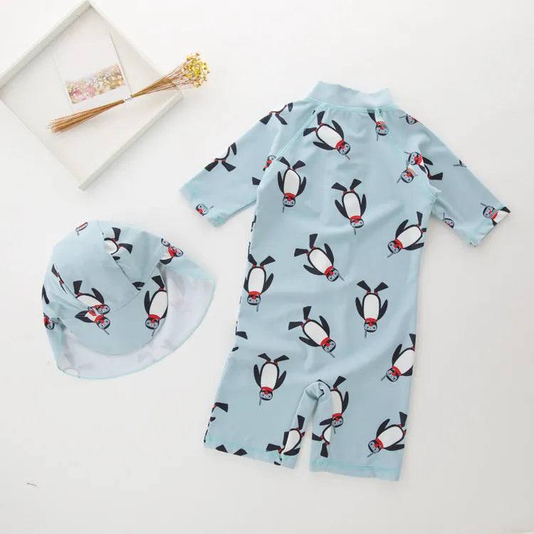 Boy's penguin print long sleeve swimsuit top and matching swim cap set on blue background