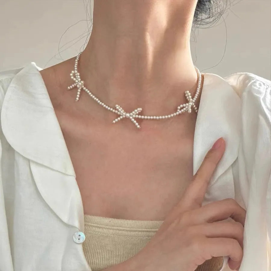 Women's white imitation pearl necklace with sweet bow design and geometric shapes on adjustable chain