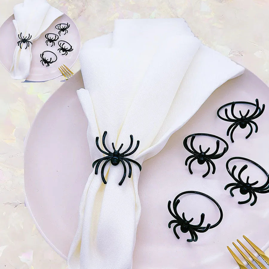 Set of six black alloy Halloween napkin rings with detailed spider design on a table setting.